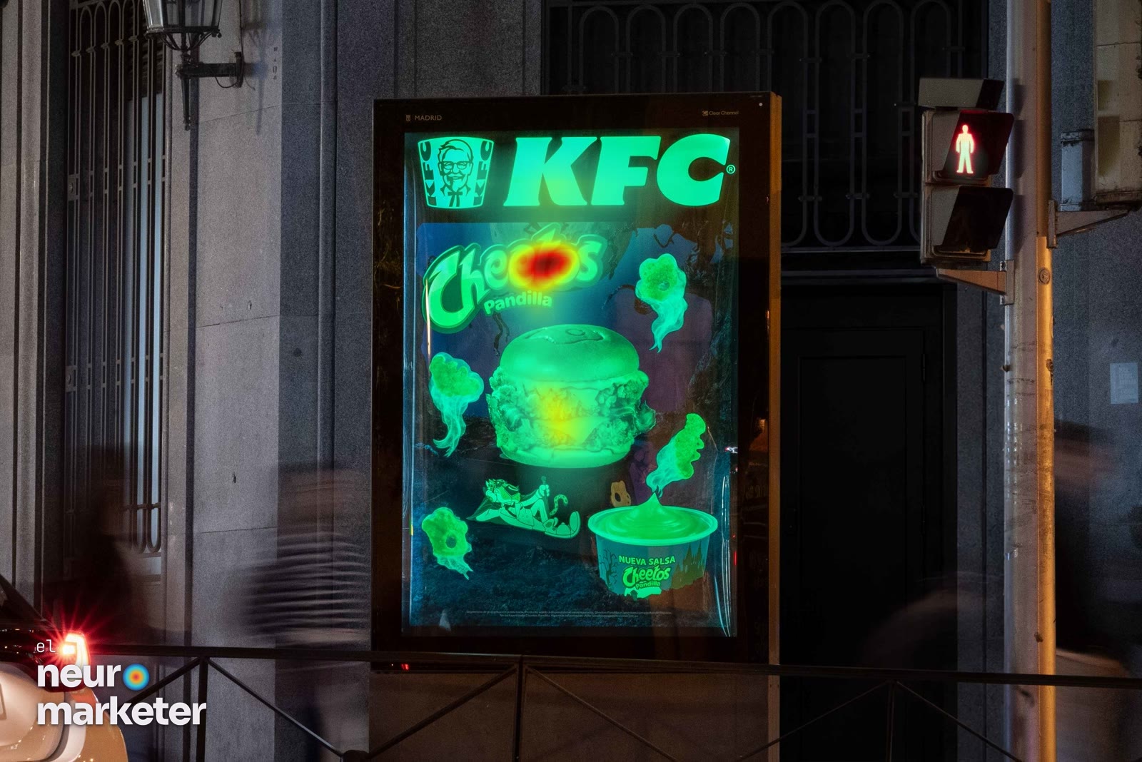 Un mupi de Madrid fotografiado de noche: sobre fondo oscuro, la marca de KFC, el logotipo de Cheetos Pandilla, la hamburguesa, la salsa y los fantasmas brillan en un mismo verde luminiscente. · Mapa de calor